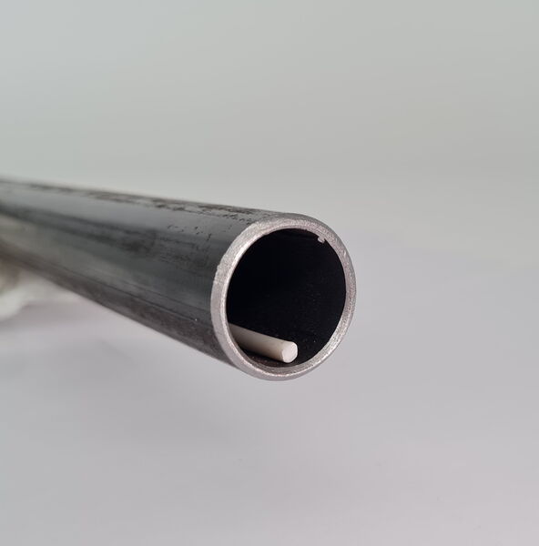 Ein Metallrohr mit nach vorn gerichteter Öffnung und innenliegendem weißen BioCor® Korrosionsschutzkabel.